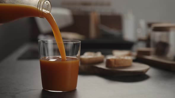 Slow Motion Pour Pumpkin Juice Into Tumbler Glass on Concrete Countertop alt