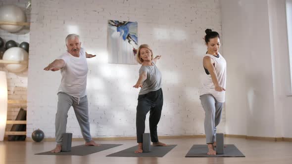 Caucasian Husband and Wife Doing Yoga with Teacher in Studio alt