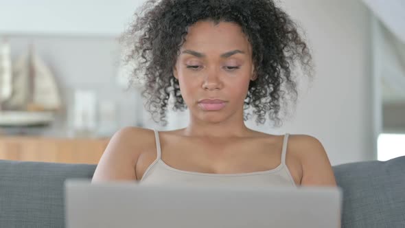 Excited African Woman Celebrating Success on Laptop alt