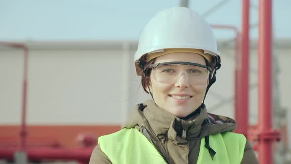 Skilled Power Engineer Woman Smiles Against Electric Station