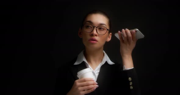 Business Woman Holds a Coffee in Her Hands and Listens to an Audio Message