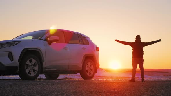 Back View of a Silhouette Man with Backpack Arms Wide Open to the Sides at Sunset alt