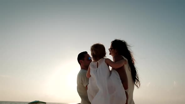 Happy Cheerful Family Walking on the Beach at a Beautiful Sunset alt