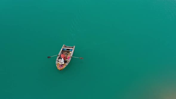 Aerial View of Wooden Boat with a Boatman Paddling Along a Turquoise Lake and His Passenger