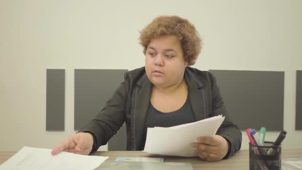 Portrait Plump Woman in Formal Wear Sitting at the Table in the Office Doing Paperwork alt