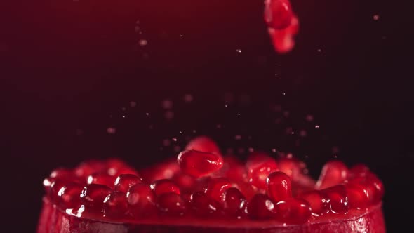 Pomegranate Grains Falling on Surface of Half Pomegranate in Slow Motion alt