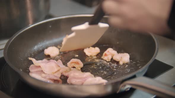 Restaurant Cooking  Chef Roasts Bacon Pieces in a Frying Pan alt