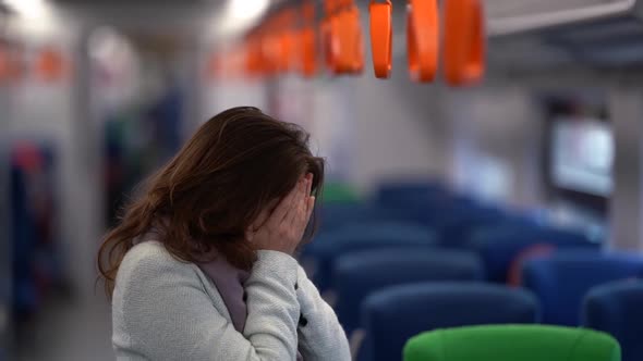 Sad Woman with Headache Is Riding in Suburban Train, Standing in Wagon, Touching Face and Head alt