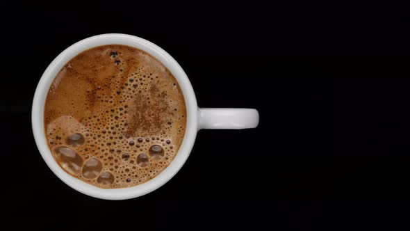 making instant black coffee in white cup, black background. alt