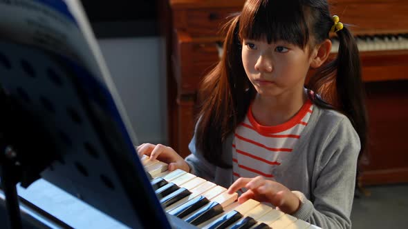 Schoolgirl learning electric piano in music class 4k alt