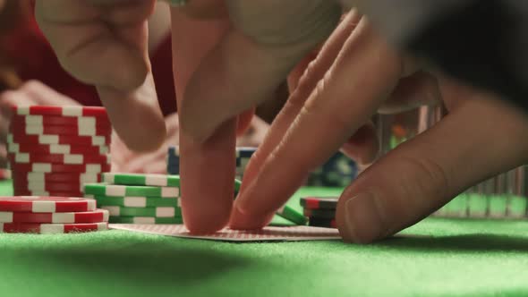 Player Checking His Poker Hand. Pair of Aces. On the Background Is Woman in Red