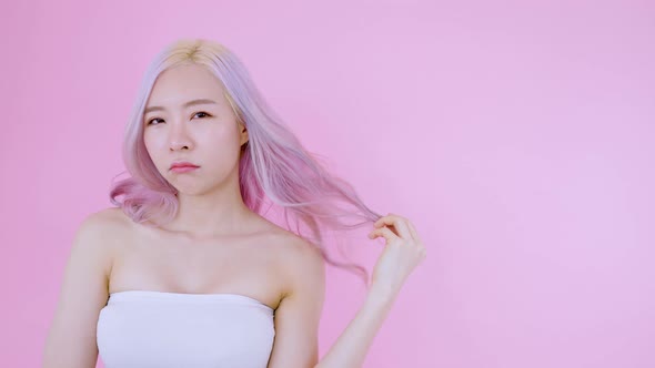Asian young woman standing and touching her hair with pink background alt