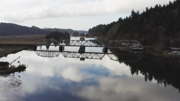 low level flight over Siuslaw river and old rail bridge in the town of Cushman, OR, USA alt