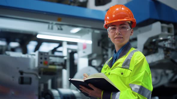 Woman Factory Worker Looking Camera Near Big Metal Manufacture Constructions alt