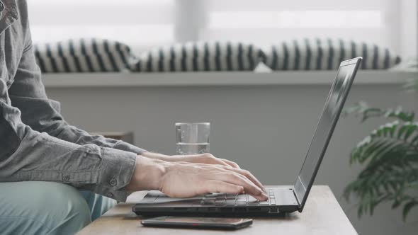 Unrecognizable Man Uses His Laptop to Work From Home alt