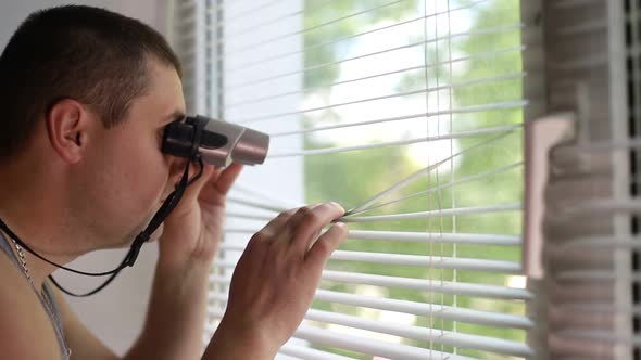 Man Spying on People Using Binoculars for Observation alt
