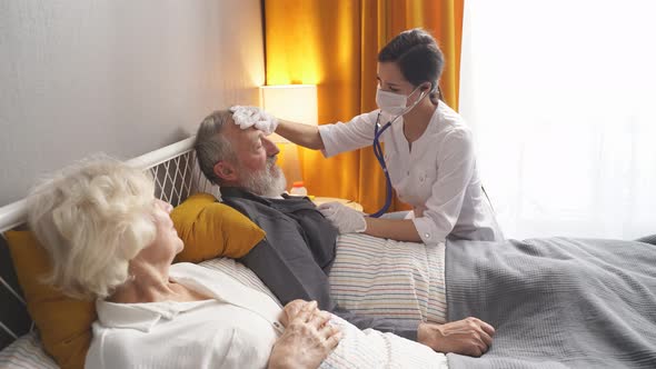 Young Nurse Take Care Senior Man on a Bed Nurse Listen to Sounds in Heart or Lungs Using Stethoscope