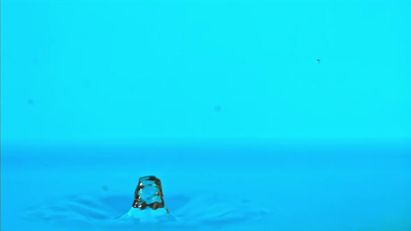 Super Slow Motion Water Falls on the Table on a Blue Background alt