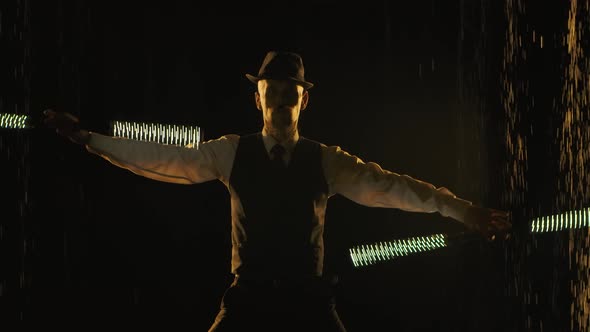 A Young Man Performs Professionally with a Fire Show and Twirls LED Sticks in a Dark Studio alt