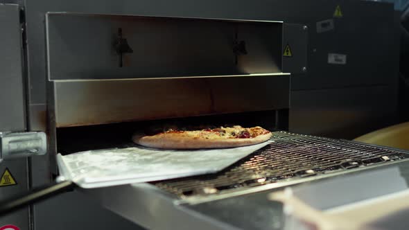 The Process Of Taking Out The Finished Pizza From A Red Hot Industrial Oven. The Process Of Cooking alt