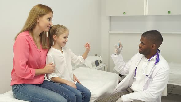 Black Male Doctor Have a Nice Talk with Kid Girl Showing Colourful Modern Capsules to Her He