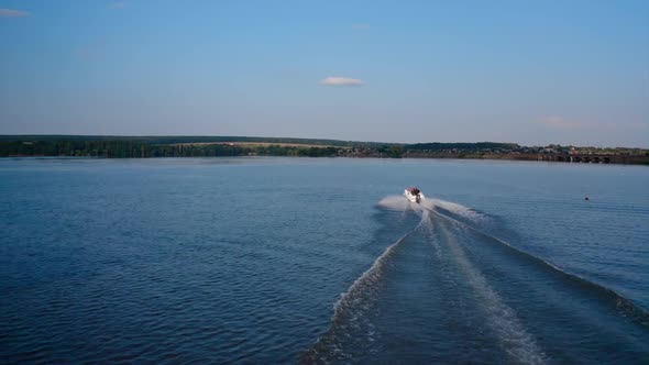 Motor boat sails along the river. Aerial view of speed boat floating on river during vacation alt