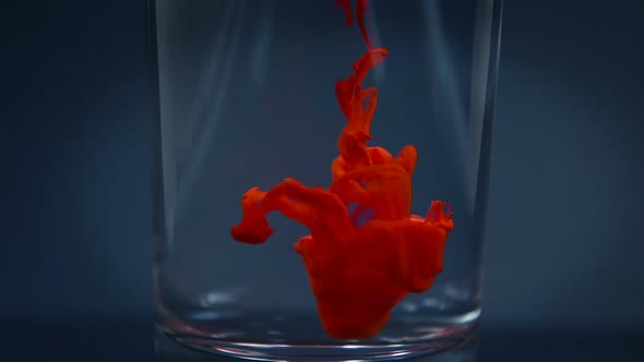 Red Paint Slowly Dissolves In A Glass Of Water.