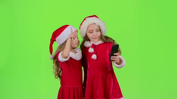 Girlfriends in an Embrace Photographed on a Smartphone. Green Screen alt