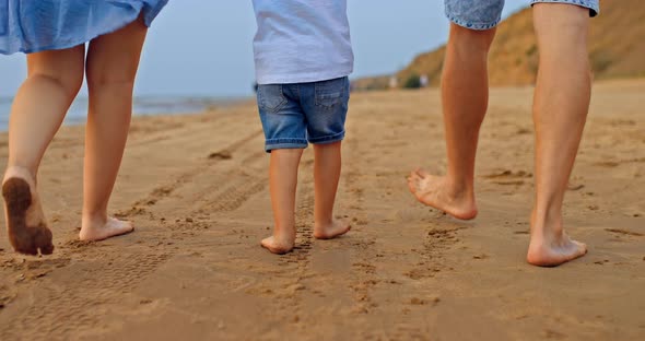 Closeup the Baby is Walking with His Bare Feet on the Sand