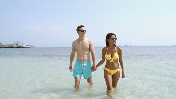 Romantic couple lover holding hands while walking at the beach in summer holiday - slow motion