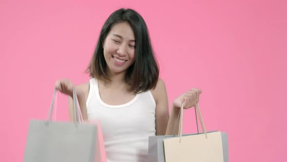 Young beautiful fashionable Asian woman holding shopping bags adorable glad woman rejoices success. alt