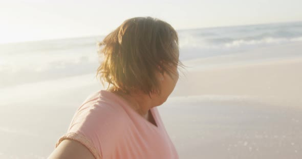 Portrait of smiling senior african american woman walking on sunny beach alt