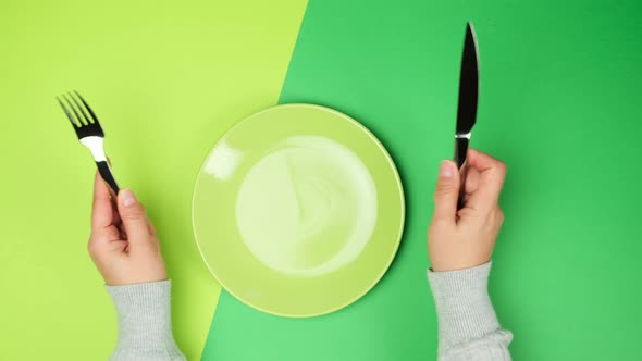 two female hands hold a metal knife and fork alt