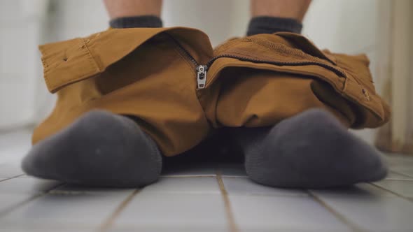 Man sitting on a toilet. Feet close up by BlackBoxGuild | VideoHive