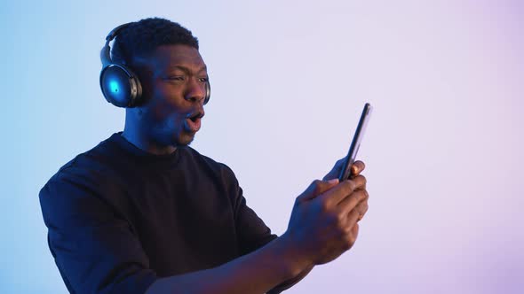 African American Man Wearing Headphones Holding a Phone in His Hand alt