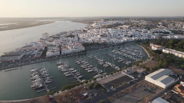 Marina in Ayamonte, Spain. Aerial pull out during sunset with historical buildings in background alt