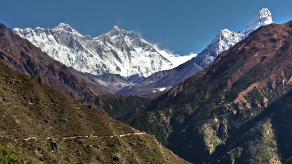 Time-lapse of Everest and surrounding peaks and people on a foreground trail. alt