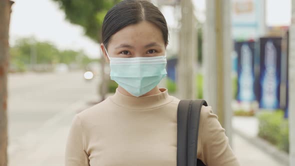 Asian woman happy smiling wearing protective face mask standing at city street.