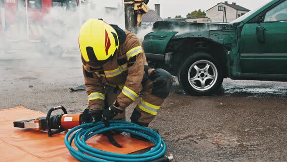 Firefighters Preparing the Hose Wor Hidraulic Cutter on the Car Crash Scene alt