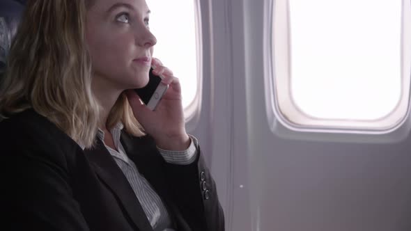 Businesswoman talking on cell phone on airplane