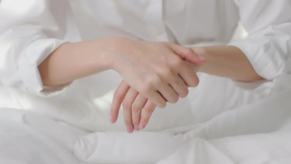 Close up of woman hand holding and applying moisturiser, Body lotion in bedroom. alt
