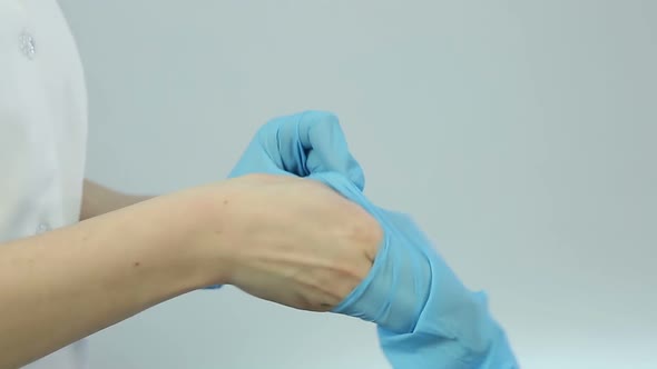 Nurse wearing medical gloves before treatment procedures, patient examination alt