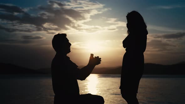 The Guy Makes a Proposal to the Girl to Get Married By the Sea at Sunset alt