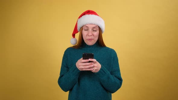 Shocked Woman in Santa Christmas Hat Holding Using Mobile Cell Phone Typing Sms