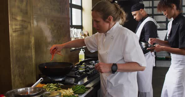 Caucasian female chef teaching diverse group preparing dishes and smiling alt
