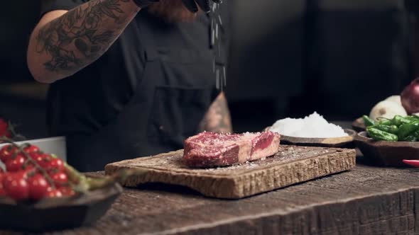 Cook man preparing steak and sprinkle salt