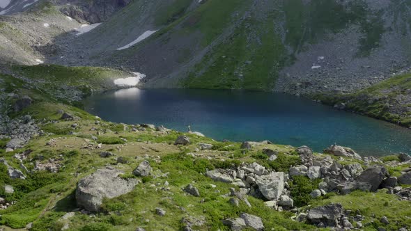 Aerial view. Woman standing near mountain emerald lake raising hands up Arkhyz North Caucasus nature