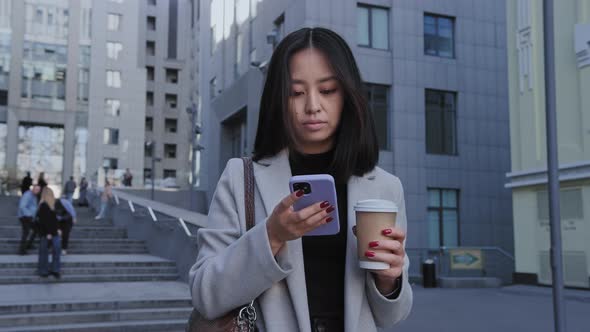 Pivoting Shot of a Young Asian Businesswoman Checking on Her Smart Phone alt