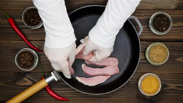 The cook puts the meat on the pan. Sliced pork in a cast iron skillet. A metal frying pan