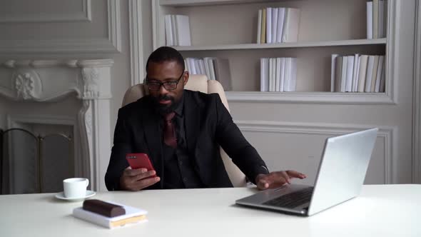 Busy Businessman Is Working in His Office, Black Man Is Sitting at Table with Laptop and Checking alt